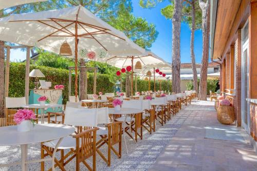 una fila de mesas y sillas con sombrillas en Hotel La Pineta Al Mare, en Forte dei Marmi