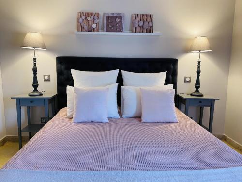 ボーム・ド・ヴニーズにあるSous Le Figuierのベッド1台(白い枕付)、テーブル2台(ランプ付)