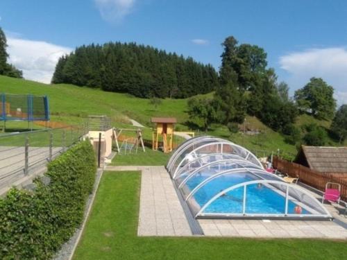 einen Pool in einem Garten mit einem Gewächshaus in der Unterkunft Ferienwohnung Kirchblick - a77305 in Liebenfels