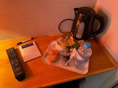 a table with a coffee pot and a bottle of water at Les 3 rois by YY in Villers-Bocage