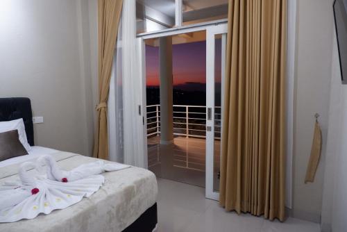 a bedroom with a bed and a view of a balcony at Gunza Bed and Breakfast by BIJAK in Jatiluwih