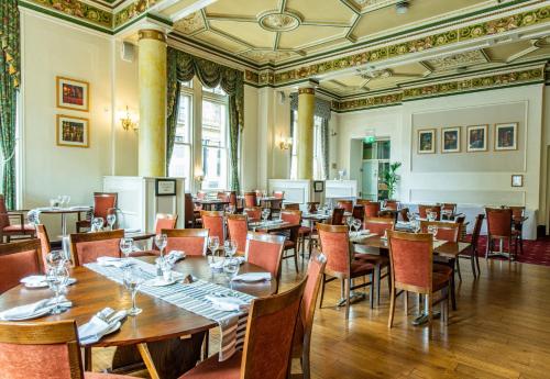 The Midland Hotel في برادفورد: غرفة طعام مع طاولات وكراسي خشبية