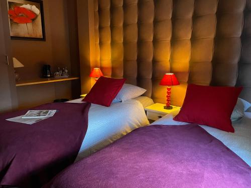 two beds in a hotel room with purple pillows at Les 3 rois by YY in Villers-Bocage