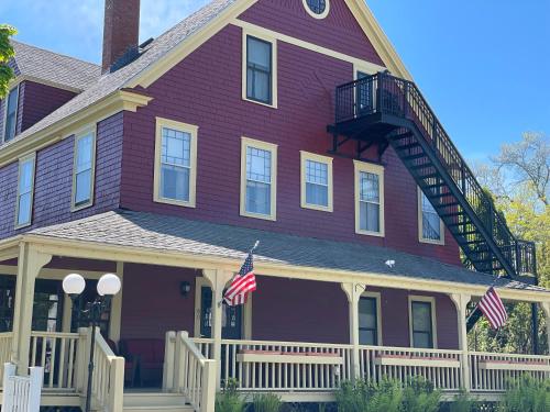 Uma casa roxa com duas bandeiras americanas. em Central House Inn em Bar Harbor