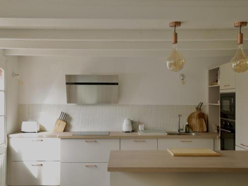 cocina con armarios blancos y encimera en La Maison Harmony, en Beuvron-en-Auge