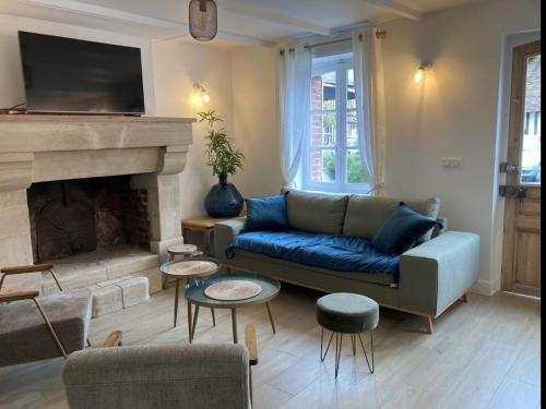 sala de estar con sofá y chimenea en La Maison Harmony, en Beuvron-en-Auge