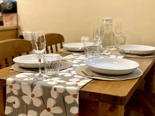 a table with plates and wine glasses on it at A spacious hidden gem with hot tub, lovely garden & views in Kington