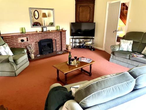 a living room with two couches and a fireplace at Little Acre, a spacious hidden gem with hot tub in Kington