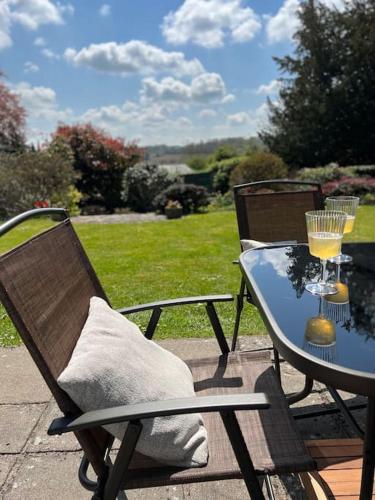 a table and chairs with a glass of wine on it at A spacious hidden gem with hot tub, lovely garden & views in Kington