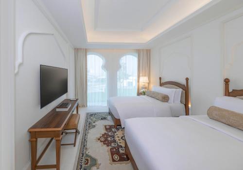 a hotel room with two beds and a flat screen tv at The Chedi Katara Hotel & Resort in Doha