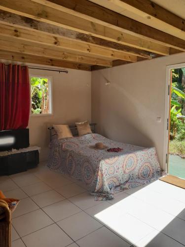 a bedroom with a bed and a large window at Un petit coin de Paradis in Deshaies