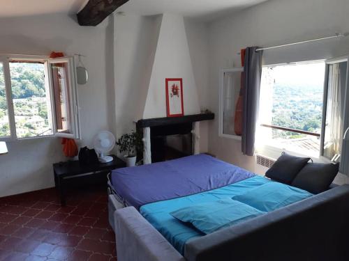 une chambre avec un lit bleu et deux fenêtres dans l'établissement Studio dans cité historique wifi et vue magnifique, à Vence