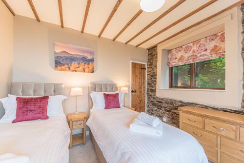 two beds in a room with two windows at Tower Cottage Far Sawrey Windermere in Far Sawrey
