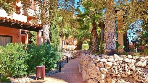 a stone wall in front of a building with trees at Luxury large 2 bedroom Apartment short walk to Villamartin Plaza in Villamartin