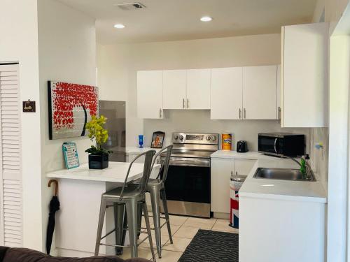 a kitchen with white cabinets and a counter with stools at Xanadu Villas - 3 Bedroom House or 2 Bedroom Apartment in Miami