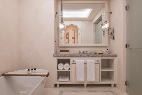 a bathroom with a tub and a sink and a mirror at The Chedi Katara Hotel & Resort in Doha