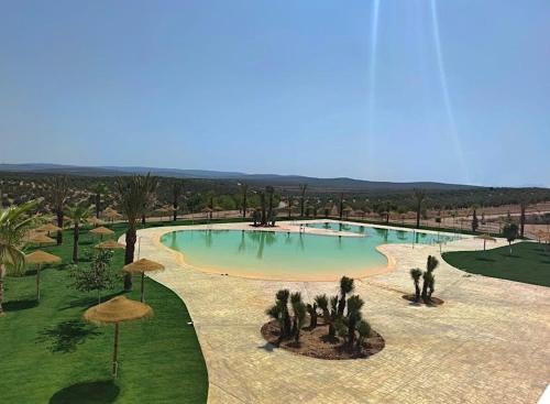 a large pool with trees and umbrellas in a park at La Casica del Abuelo Valentín 