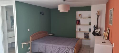 - une chambre avec un lit et un mur vert dans l'établissement Studio en plein coeur de Chanac, à Chanac