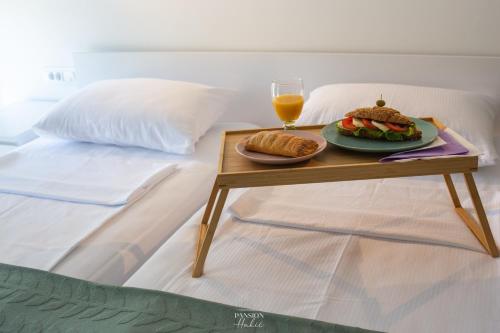 a table with a sandwich and a drink on a bed at Pansion Hukić B&B in Tuzla