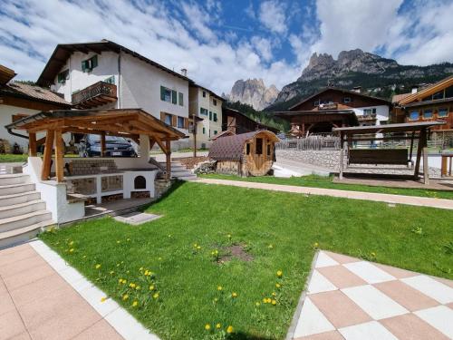 un cortile con prato, un edificio e le montagne di Residence Le Rose a Pozza di Fassa