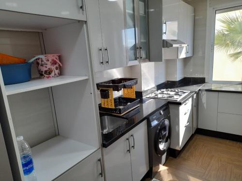 a kitchen with white cabinets and a washer and dryer at appartement NADOR wifi gratuit clima mobile in Nador