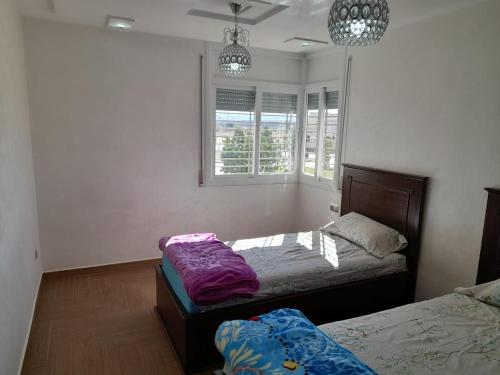 een slaapkamer met 2 bedden en 2 ramen bij appartement NADOR wifi gratuit in Nador