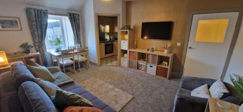 sala de estar con sofá y TV en Mains Street Retreat en Lockerbie