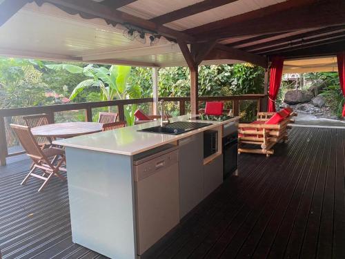 eine Küche auf einer Terrasse mit einem Tisch und Stühlen in der Unterkunft Le Domaine du Rocher Noir in Pointe-Noire