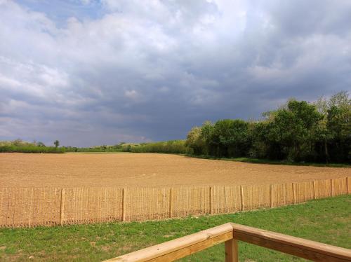 una cerca frente a un campo con un campo de tierra en Bulle SPA Romantique, en Jarcieu