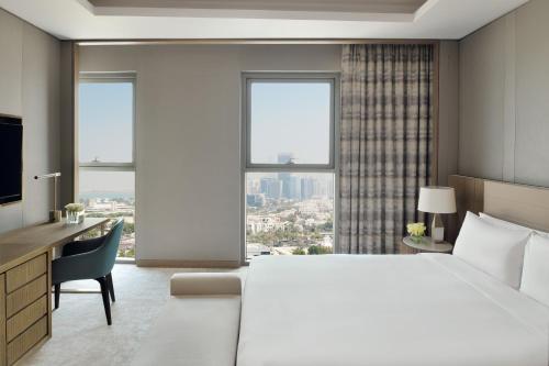 a hotel room with a large bed and a desk and window at InterContinental Residences Abu Dhabi, an IHG Hotel in Abu Dhabi