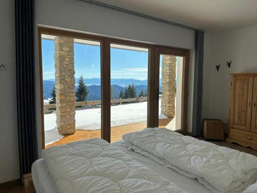 a bedroom with a bed and a large glass window at Reimers Chalets Hochrindl in Hochrindl