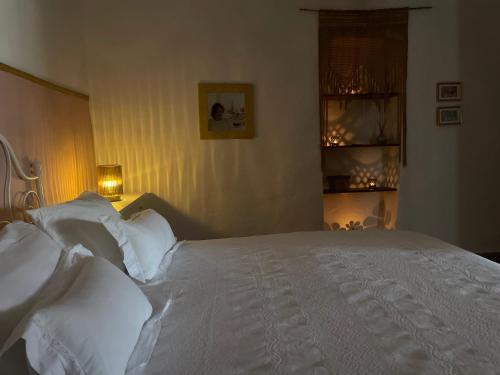 Schlafzimmer mit einem Bett mit weißer Bettwäsche und Kissen in der Unterkunft Marisa Home in Orzola