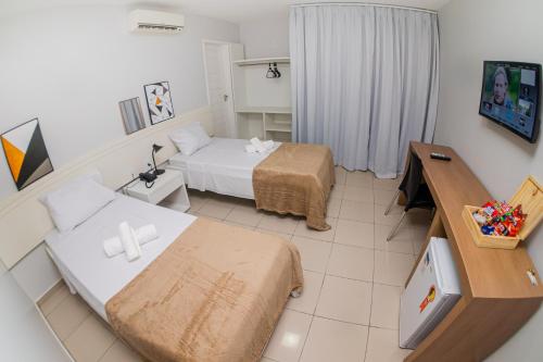 a small room with two beds and a desk at Hotel Rochedo AL in Penedo