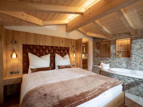 a bedroom with a large bed and a tub at Luxusappartement Alpenliebe in Oberndorf in Tirol