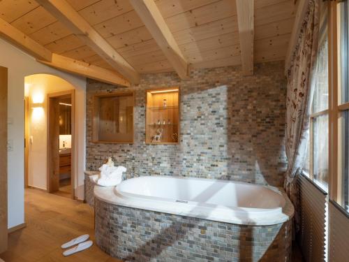 y baño con bañera y pared de ladrillo. en Luxusappartement Alpenliebe, en Oberndorf in Tirol