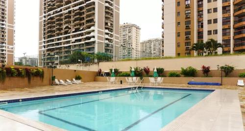 a swimming pool on the roof of a building with tall buildings at Flat Barra - Liberty Place in Rio de Janeiro