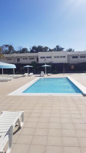 a swimming pool with a bench in front of a building at Apartamento Relax in Arona