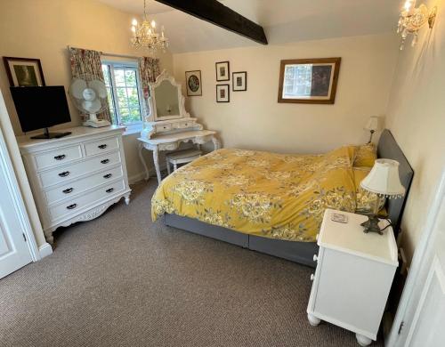 een slaapkamer met een bed, een dressoir en een bureau bij Beech View Cottage in Downham Market