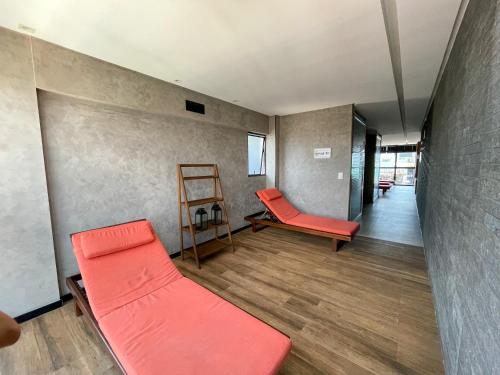 a living room with two red chairs and a ladder at Studio Time 1312 - Luxo - Ponta Verde - Maceió-AL in Maceió