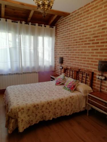 una camera con letto e muro di mattoni di Casa del patio a Villanueva de Valdueza