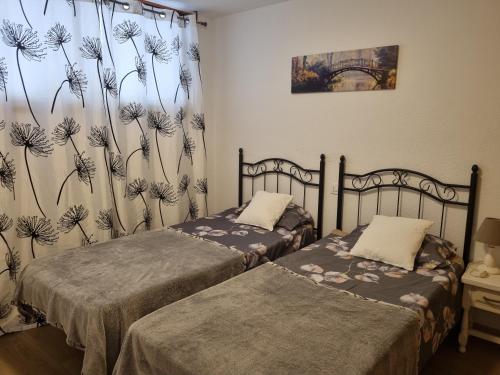 プエルト・デ・サンティアゴにあるApartment Los Gigantesのベッドルーム1室(ベッド2台、タンポポのカーテン付)