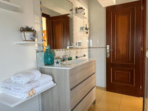 a bathroom with a sink and a mirror and towels at Apartamento vacacional Poio-Rias Baixas in Poio