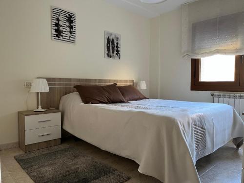a white bedroom with a bed and a nightstand and a window at Apartamento vacacional Poio-Rias Baixas in Poio