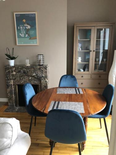 une salle à manger avec une table en bois et des chaises bleues dans l'établissement L'Aiguillon, bel appartement hyper-centre, à Brest