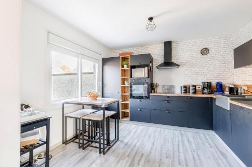 une cuisine avec des armoires bleues et une table dans l'établissement Le Gîte des 5 étangs, à Bouvaincourt-sur-Bresle