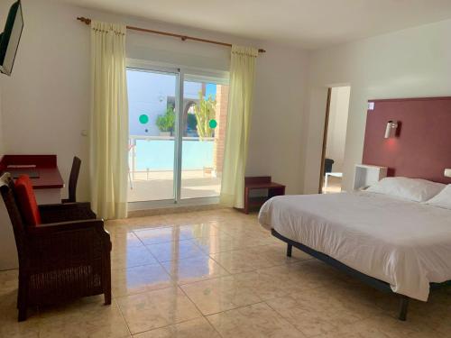 a bedroom with a bed and a chair and a pool at Hospedium Hotel Continental in Mojácar