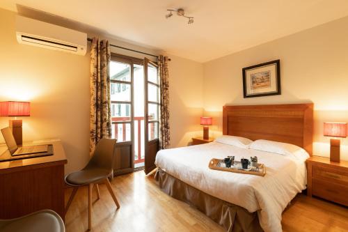 a hotel room with a bed and a desk and a window at Hôtel Lastiry in Sare