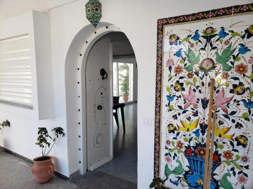 a hallway with a door with a floral wall at Maison du Cap Bon,Ben Hamida in El Haouaria