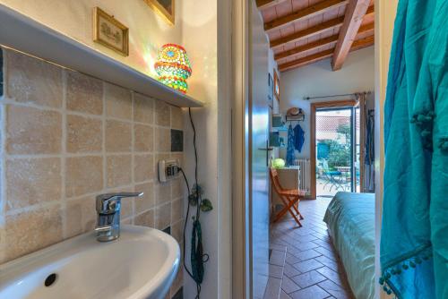 a bathroom with a sink and a bed in a room at Casetta delle mimose in Seccheto