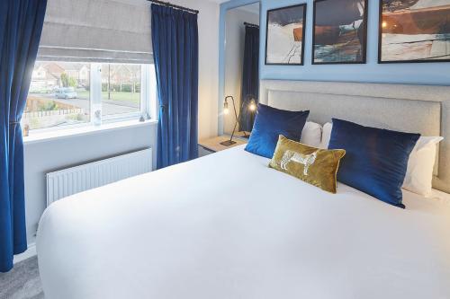 sypialnia z białym łóżkiem z niebieskimi poduszkami i oknem w obiekcie Host & Stay - Benton Road w mieście Newcastle upon Tyne